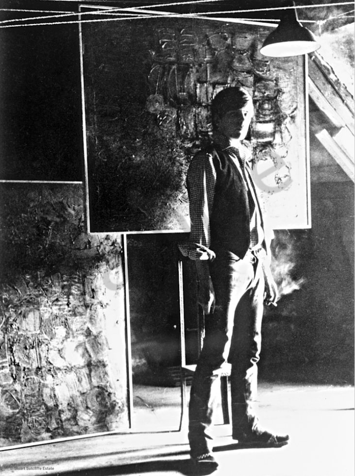 Self Portrait — a black-and-white photograph of Stuart Sutcliffe standing before his work